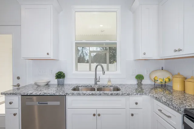 a kitchen with granite countertop white cabinets and a sink