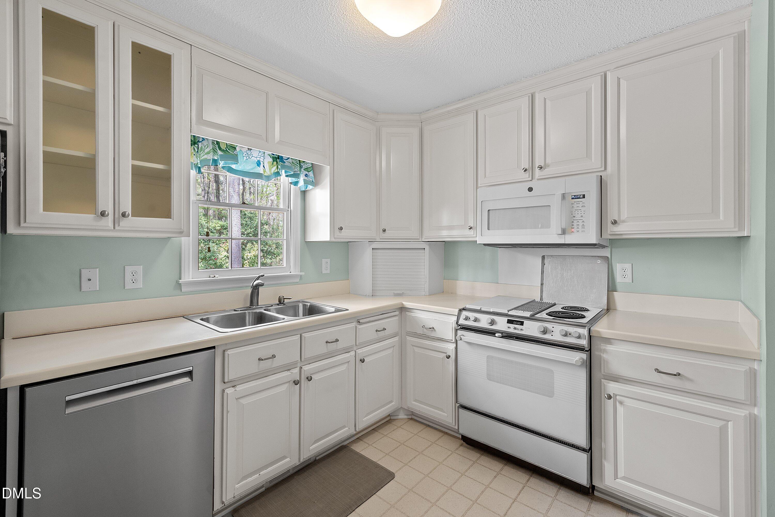 1429 Falls Church Road Raleigh, NC 27609 - Photo 26 of 60 a kitchen with white cabinets and white appliances