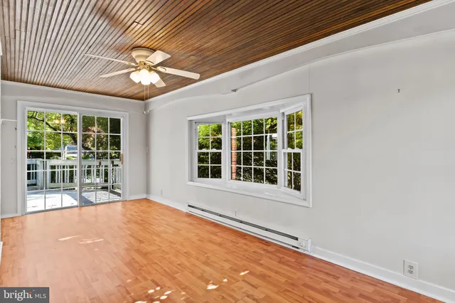 a view of an empty room with window and wooden floor