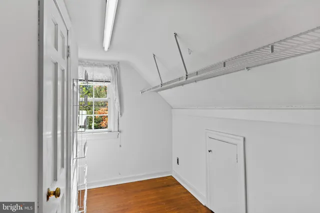 an empty room with wooden floor closet and windows