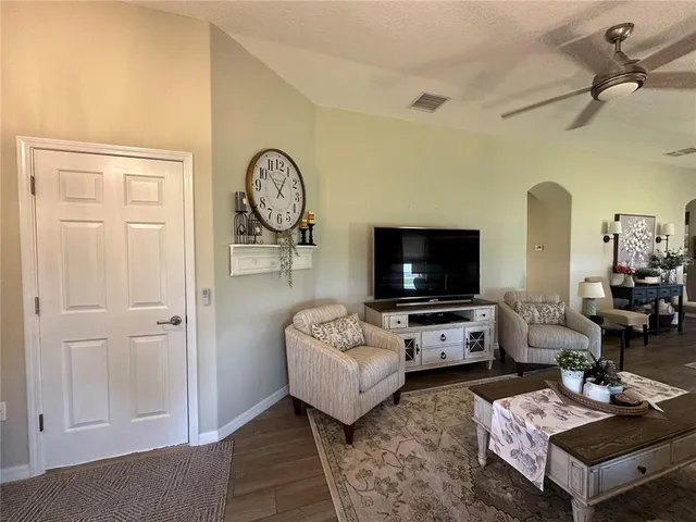 a living room with furniture a clock and a ceiling fan