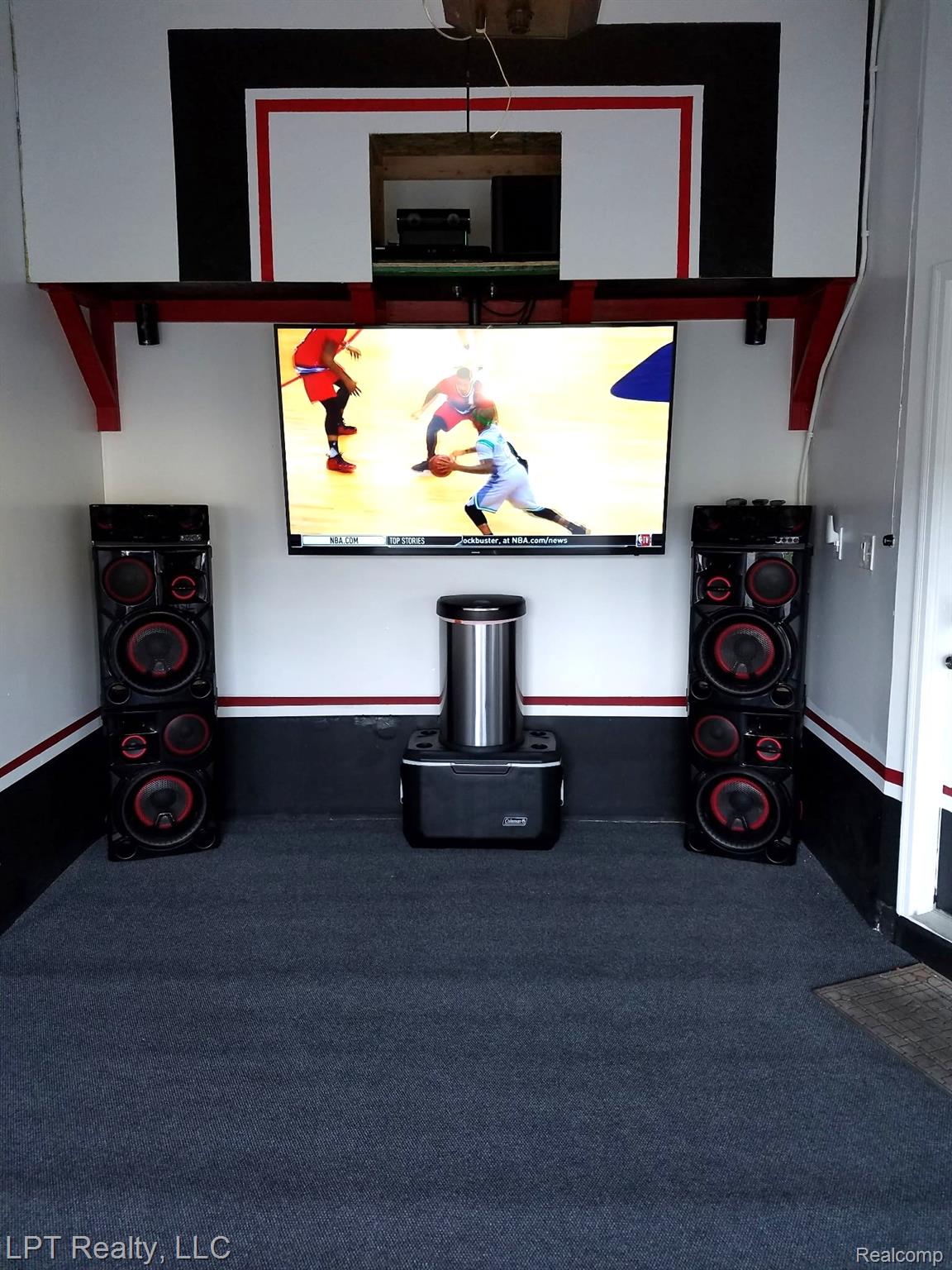 3304 Spinnaker Lane, Unit 47 Detroit, MI 48207 - Photo 18 of 21 Garage space featuring a basketball backboard motif, wall-mounted television, dark gray carpet flooring, and white walls with red and black accents