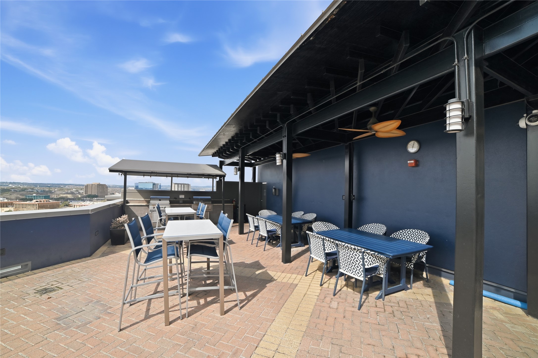 54 Rainey Street, Unit 1018 Austin, TX 78701 - Photo 28 of 32 a roof deck with table and chairs under an umbrella with a barbeque