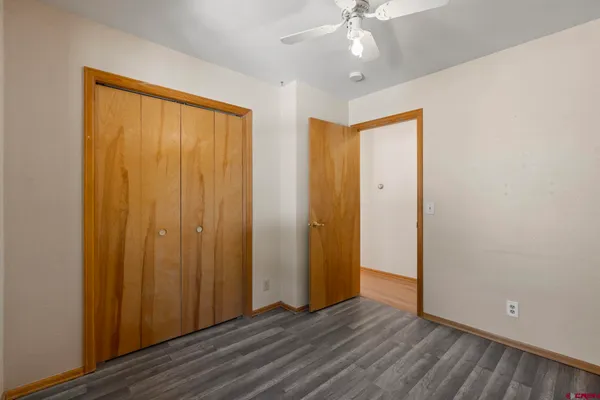 an empty room with wooden floor closet and windows