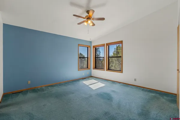 a view of an empty room with window and chandelier fan