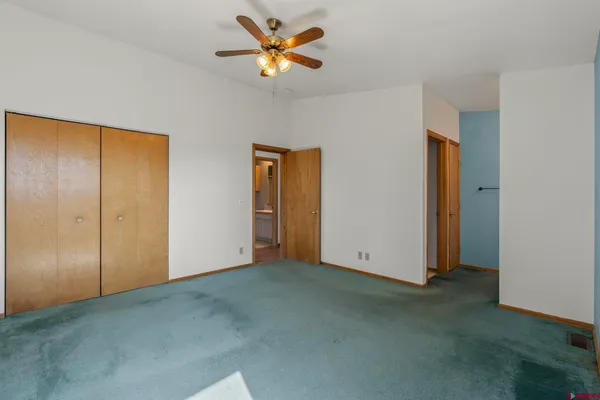 an empty room with closet and a chandelier fan