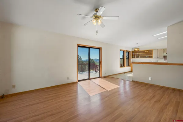 a view of an empty room with a window and wooden floor