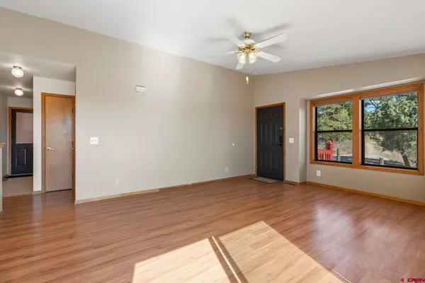 a view of an empty room with window and wooden floor