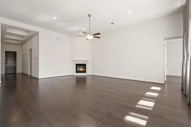 an empty room with wooden floor and chandelier fan