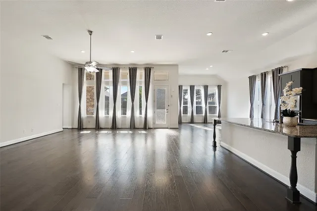 an empty room with wooden floor fireplace and windows