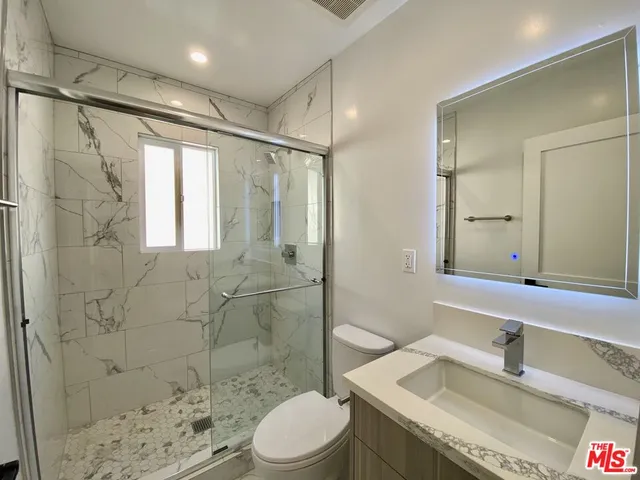 a bathroom with a granite countertop sink toilet and shower