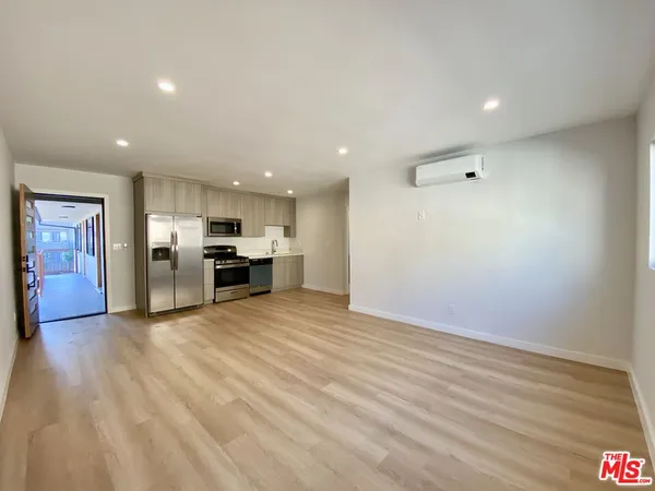 a view of kitchen with kitchen island wooden floor center island and stainless steel appliances
