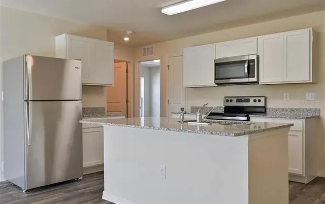 a kitchen with stainless steel appliances granite countertop a refrigerator a stove top oven a sink and dishwasher