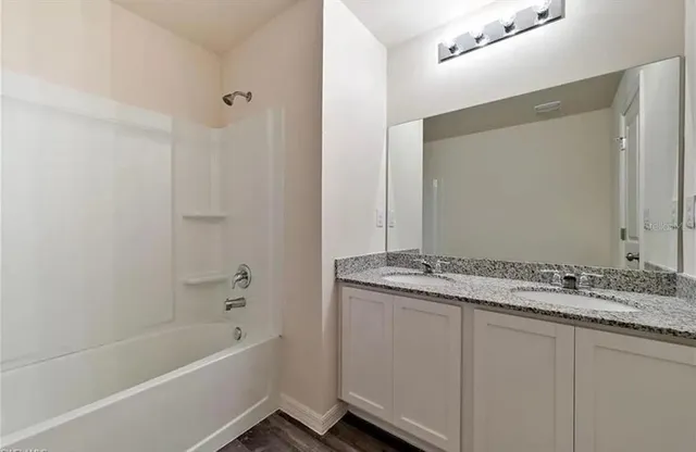 a bathroom with a granite countertop sink a mirror and a bathtub