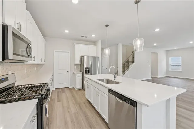 a large kitchen with stainless steel appliances granite countertop a stove a sink a refrigerator and a wooden floor