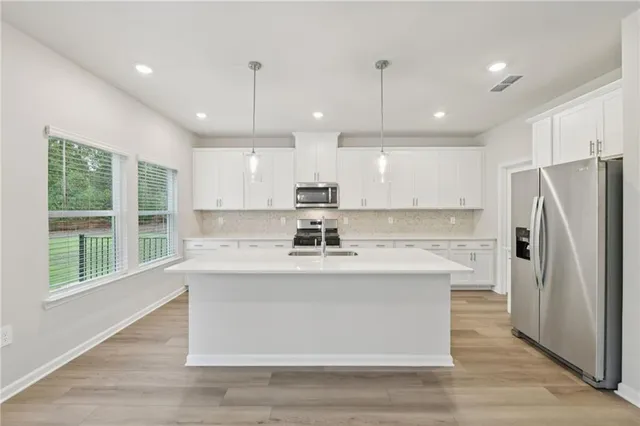 a kitchen that has a lot of white cabinets and stainless steel appliances