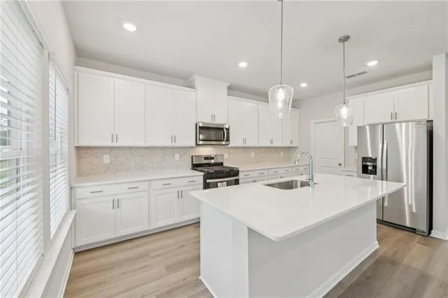 a kitchen with stainless steel appliances white cabinets and a stove top oven