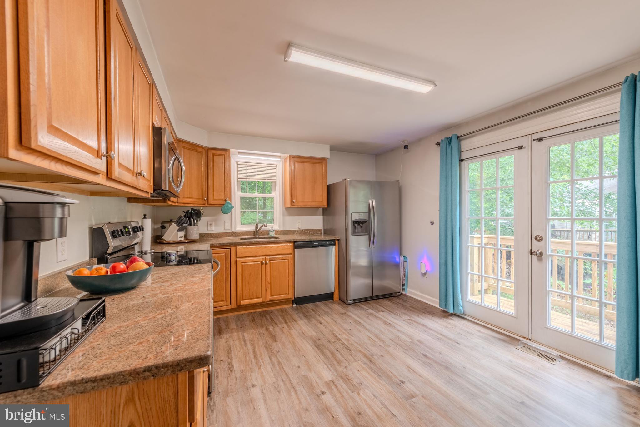 668 Running Fox Road Lusby, MD 20657 - Photo 4 of 12 a kitchen with stainless steel appliances granite countertop wooden floors a stove and a refrigerator