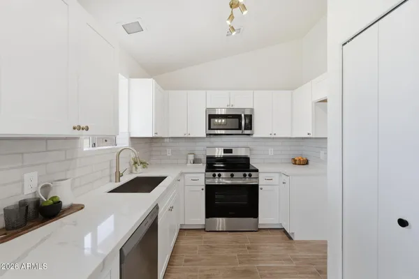 a kitchen with white cabinets and appliances