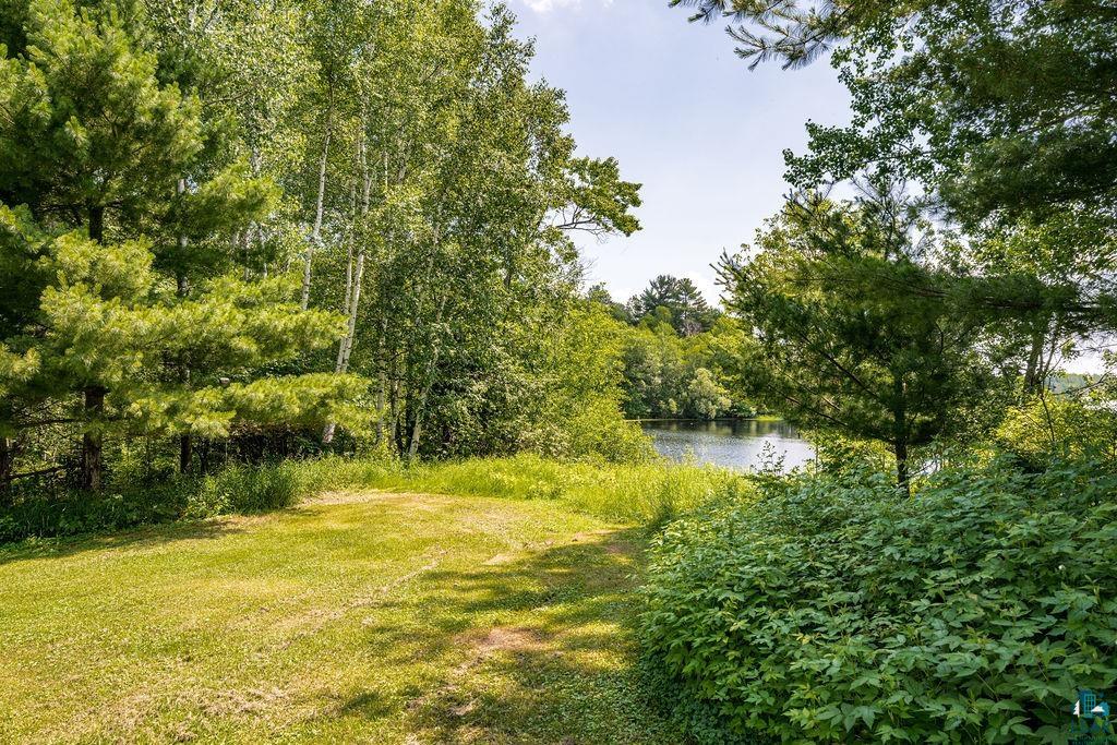 2592 Strandberg Road Barnum, MN 55707 - Photo 24 of 44 Expansive outdoor space featuring a manicured lawn, lush green foliage, mature trees, and a visible body of water