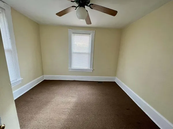 an empty room with a window and a ceiling fan