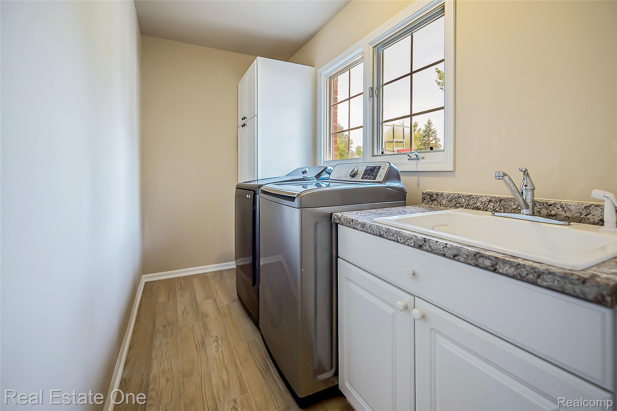 1013 Rochelle Park Drive Rochester, MI 48307 - Photo 23 of 74 Utility room featuring wood-finish flooring, built-in cabinetry, a utility sink with a chrome faucet, and a window with grid detailing