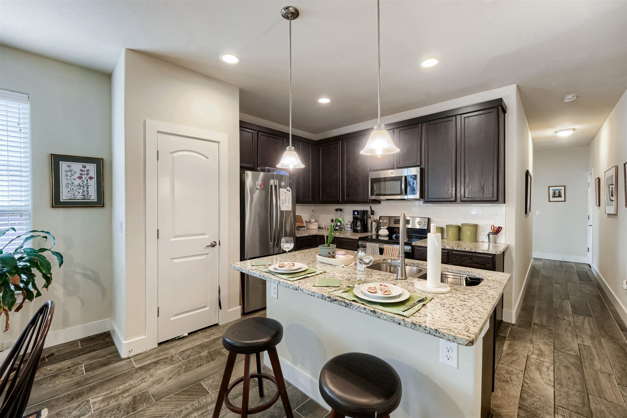 418 High Tech Drive Georgetown, TX 78626 - Photo 10 of 34 Kitchen featuring dark wood cabinetry, stainless steel appliances, and a granite-finish island with pendant lighting