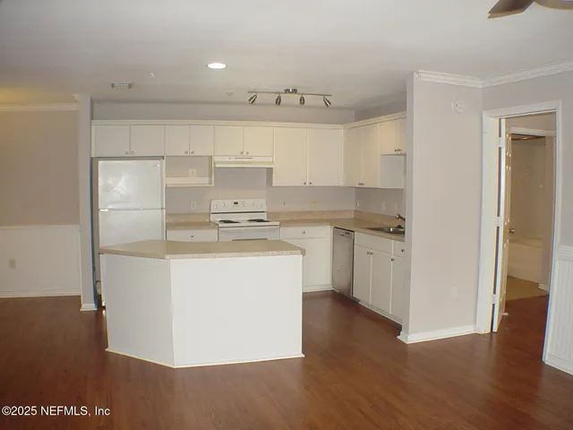 a kitchen with kitchen island white cabinets and stainless steel appliances