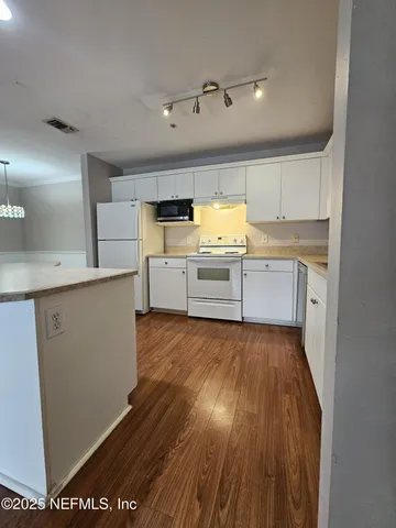 a kitchen with wooden floors and white cabinets
