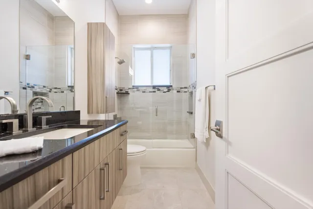 a bathroom with a granite countertop sink a mirror and a bathtub