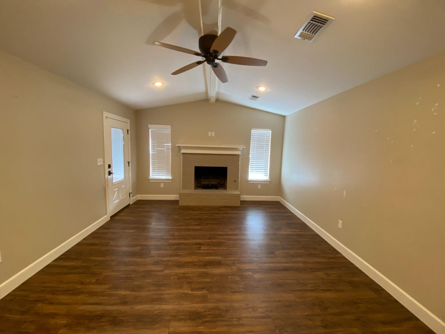 3235 64th Street Lubbock, TX 79413 - Photo 3 of 11 an empty room with wooden floor fireplace and windows