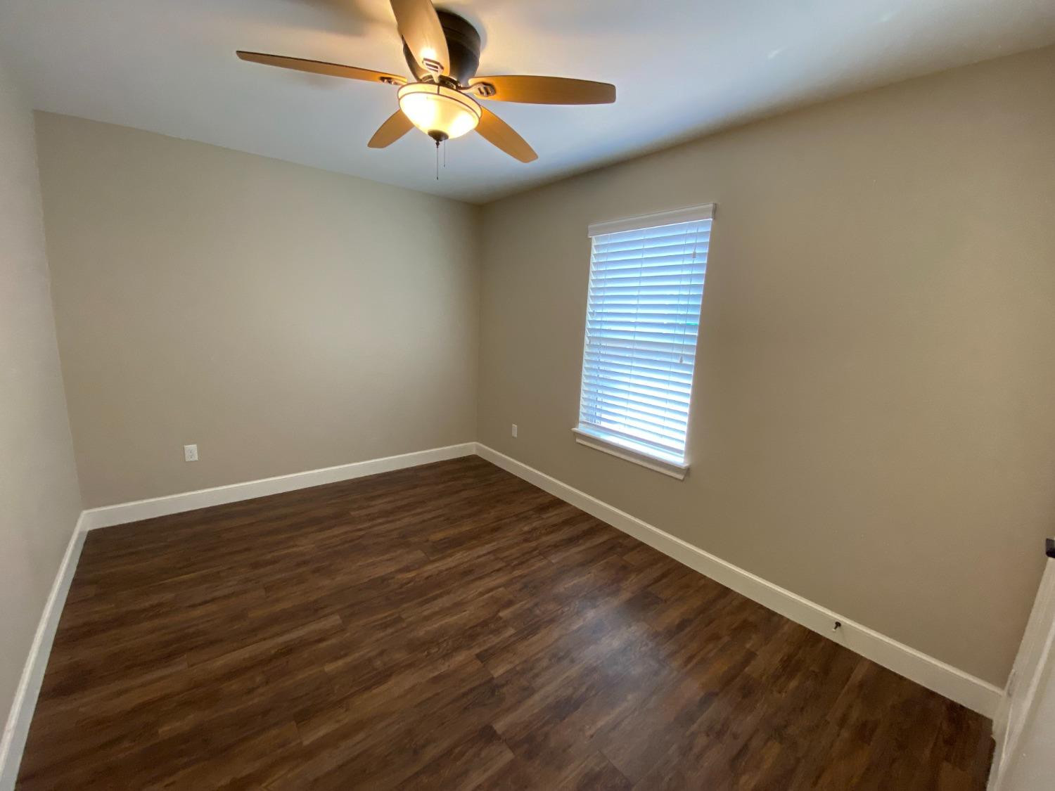 3235 64th Street Lubbock, TX 79413 - Photo 6 of 11 an empty room with wooden floor fan and windows