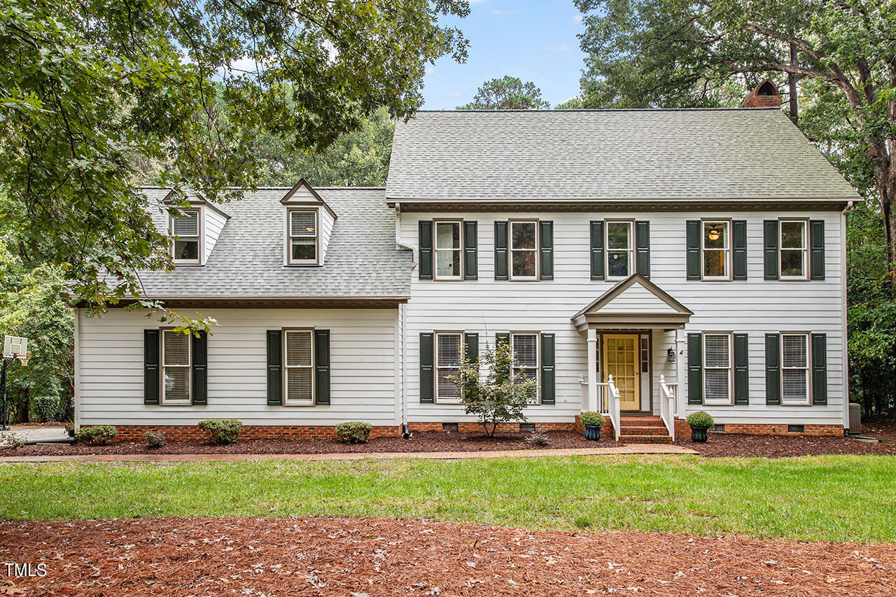 a front view of a house with a garden and trees