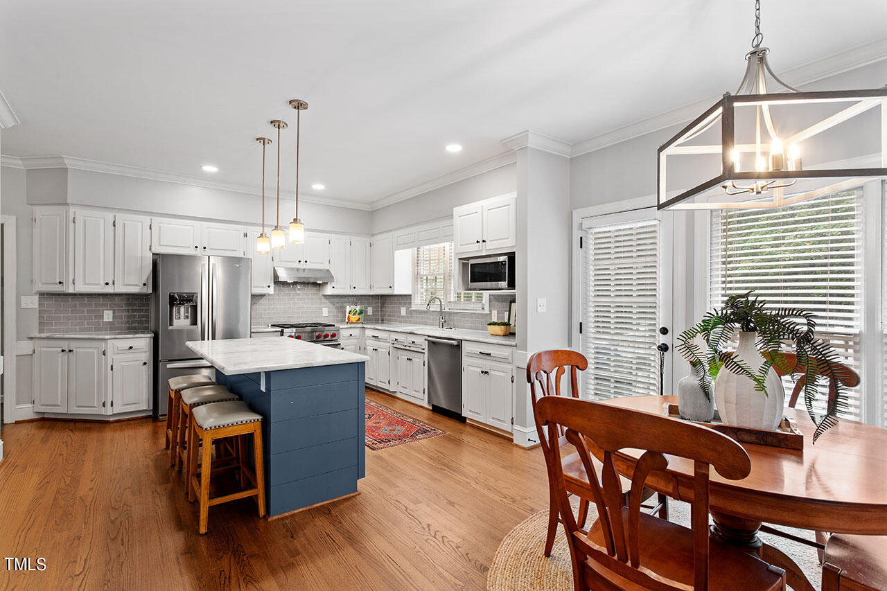 2408 Heartley Drive Raleigh, NC 27615 - Photo 13 of 41 a kitchen with stainless steel appliances granite countertop a refrigerator a sink dishwasher a stove and a dining table with wooden floor