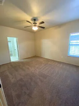 an empty room with a window and a ceiling fan