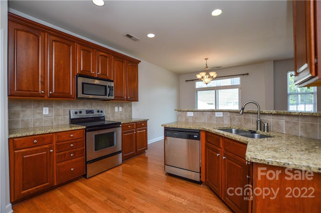 12110 Red Rust Lane Charlotte, NC 28277 - Photo 11 of 36 a kitchen with stainless steel appliances granite countertop wooden cabinets and a stove top oven