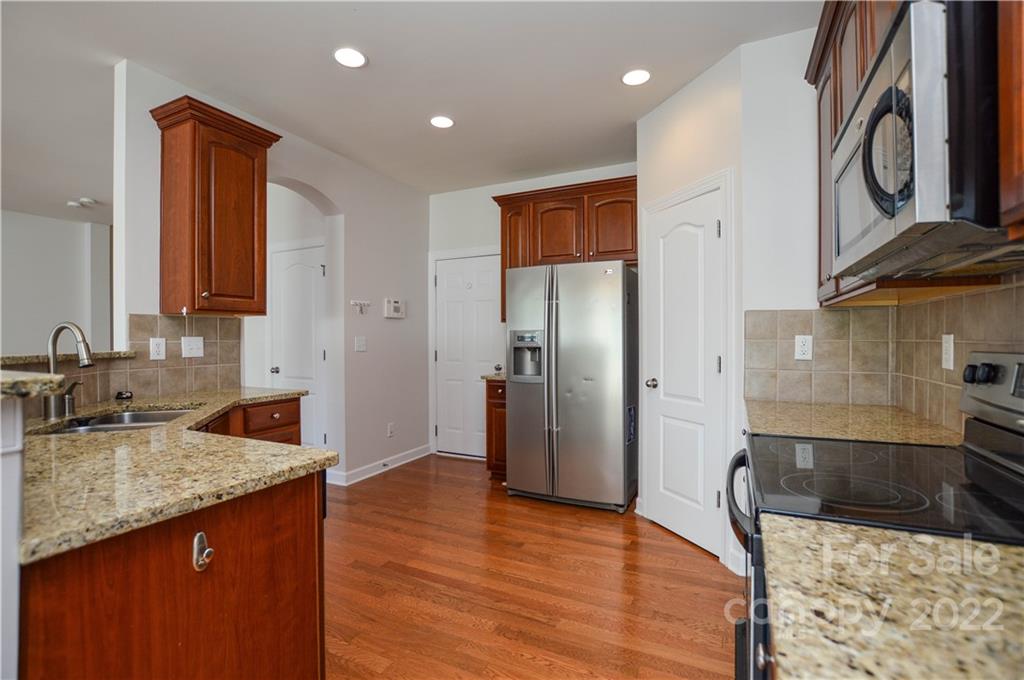 12110 Red Rust Lane Charlotte, NC 28277 - Photo 12 of 36 a kitchen with stainless steel appliances granite countertop a refrigerator a stove and a sink with wooden floor