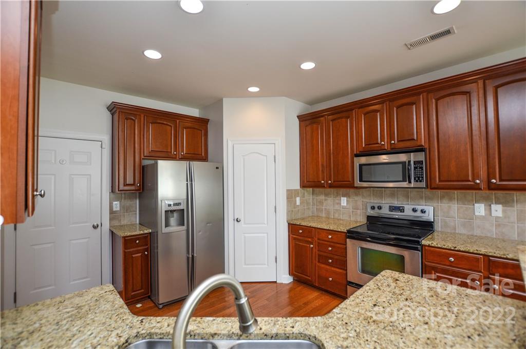 12110 Red Rust Lane Charlotte, NC 28277 - Photo 10 of 36 a kitchen with granite countertop wooden cabinets a refrigerator and a stove top oven