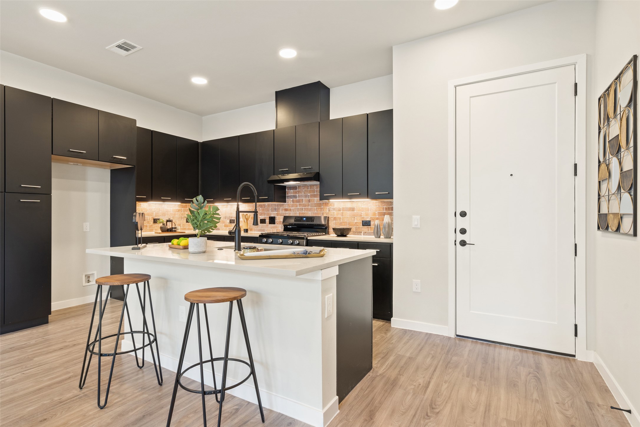 4510 Terry-O Lane, Unit 341 Austin, TX 78745 - Photo 8 of 40 The kitchen features sleek black cabinetry, a central island with a light-toned countertop, and a brick-patterned backsplash