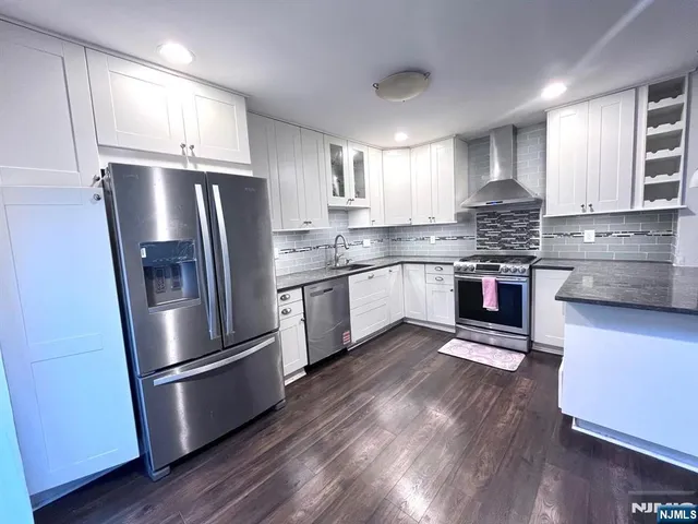 a kitchen with stainless steel appliances wooden floor sink and wooden cabinets