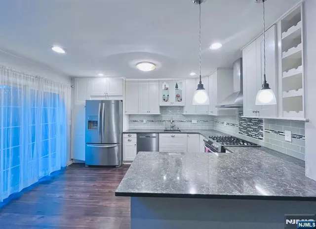 a kitchen with kitchen island a counter top space a sink stainless steel appliances and cabinets
