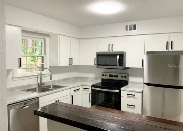 a kitchen with granite countertop a sink appliances and cabinets