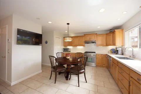 a kitchen with a dining table chairs and white appliances