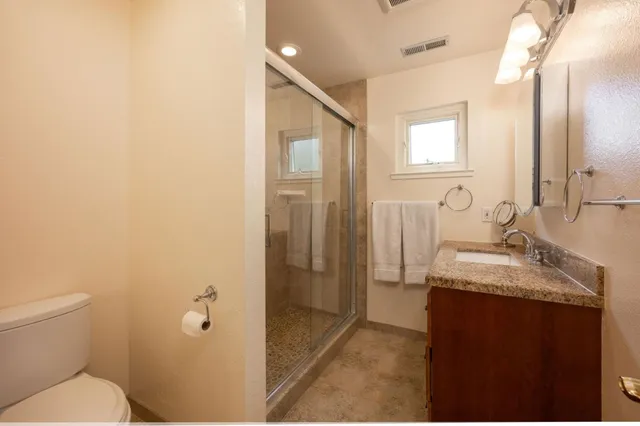 a bathroom with a granite countertop sink toilet and shower