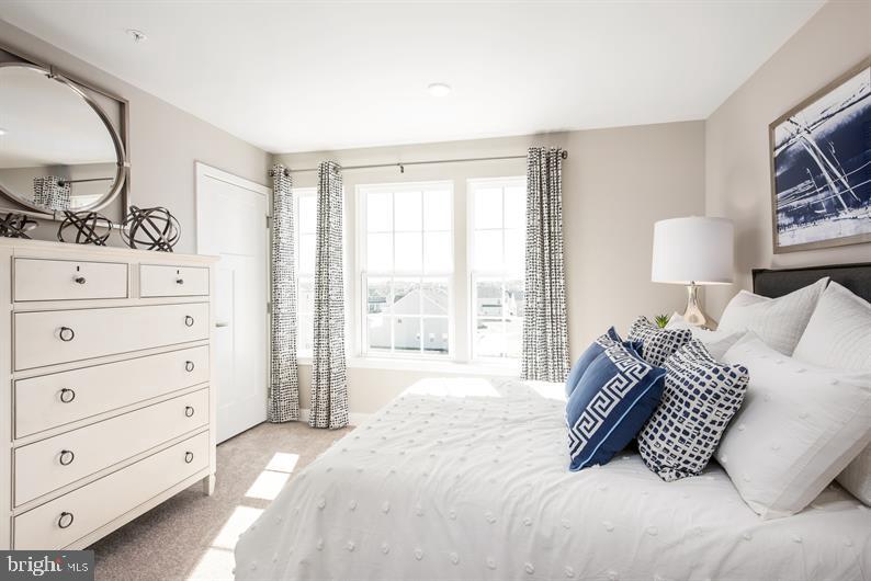 131 Drydock Way, Unit H Brooklyn, MD 21225 - Photo 10 of 13 a bedroom with a bed a lamp and closet with mirror