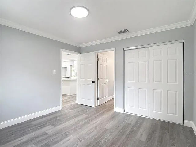 an empty room with wooden floor & closet area