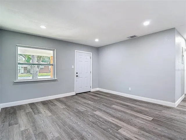 a large white kitchen with wooden floor and stainless steel appliances