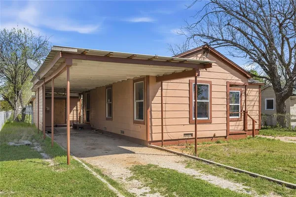 a view of a white house with a small yard and large tree