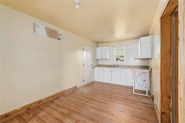 a large white kitchen with white cabinets and wooden floor