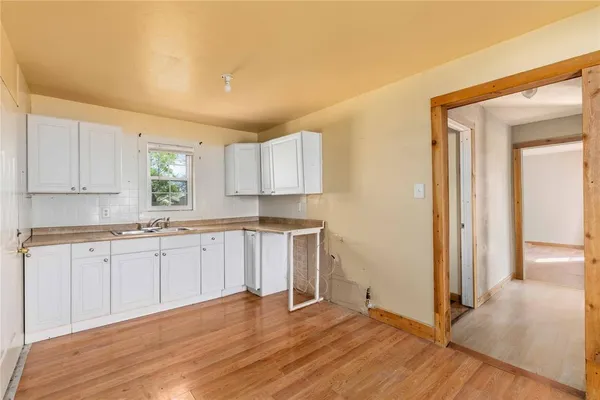 a kitchen with granite countertop white cabinets and wooden floor